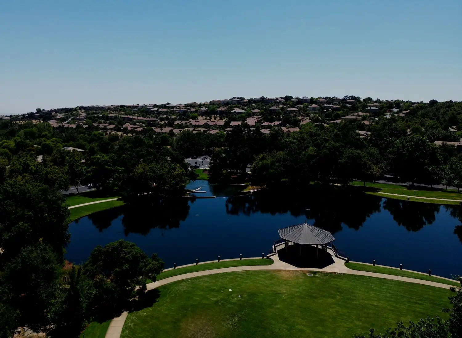 Aerial view of a lake and green parkland in a hillside community