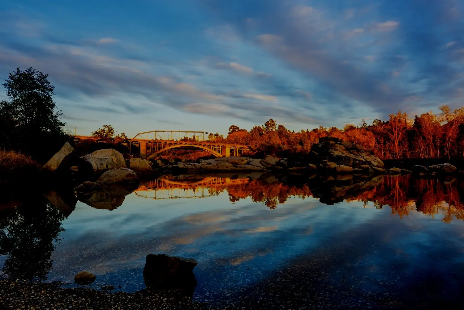 River and autumn foliage mirrored in still water at sunset