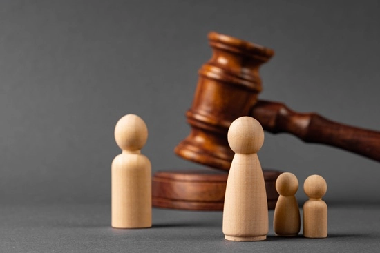 Wooden family figurines standing before a gavel