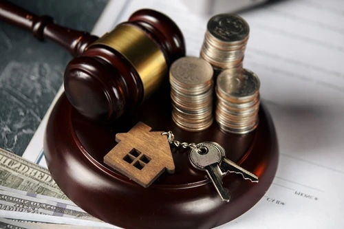 Gavel with stacked coins, a house charm and keys