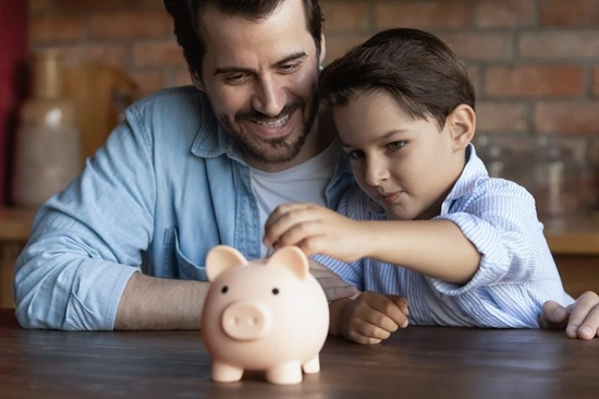 Father and son dropping a coin into a piggy bank