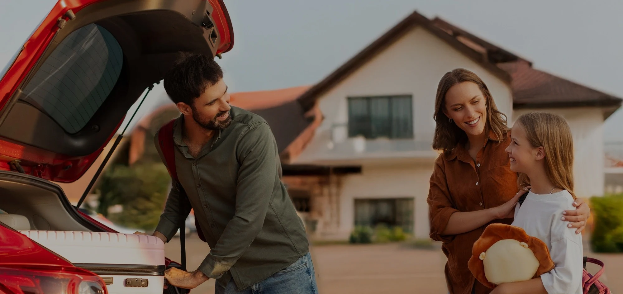 Family loading moving boxes into a car outside their house