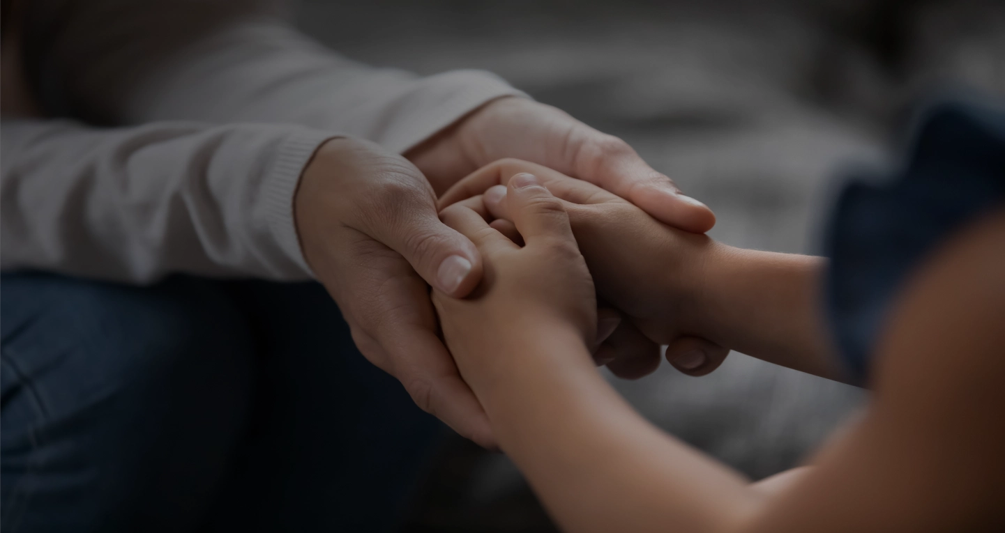 Adult hands gently holding a child's hands