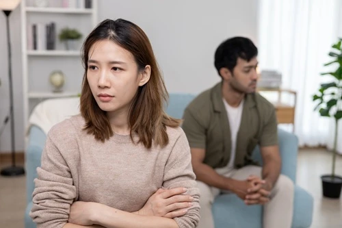 Couple sitting apart on a sofa, both looking away