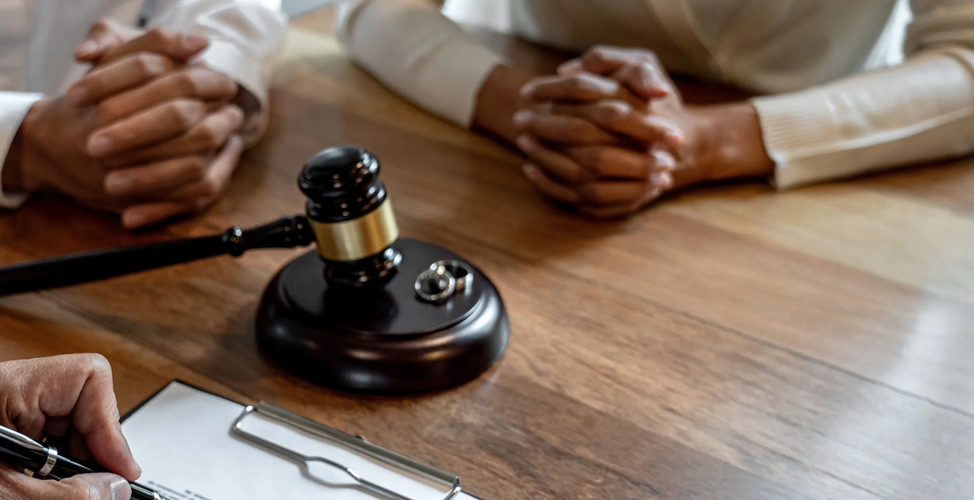 Two people with clasped hands at a table beside a gavel