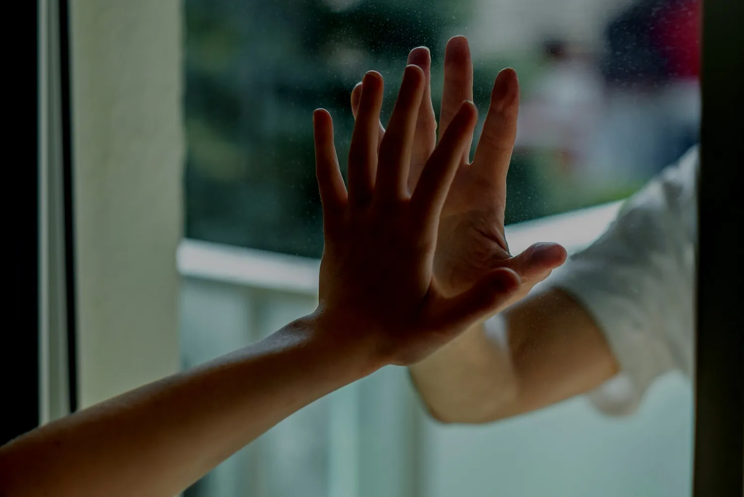 Child's hand pressed against a window pane