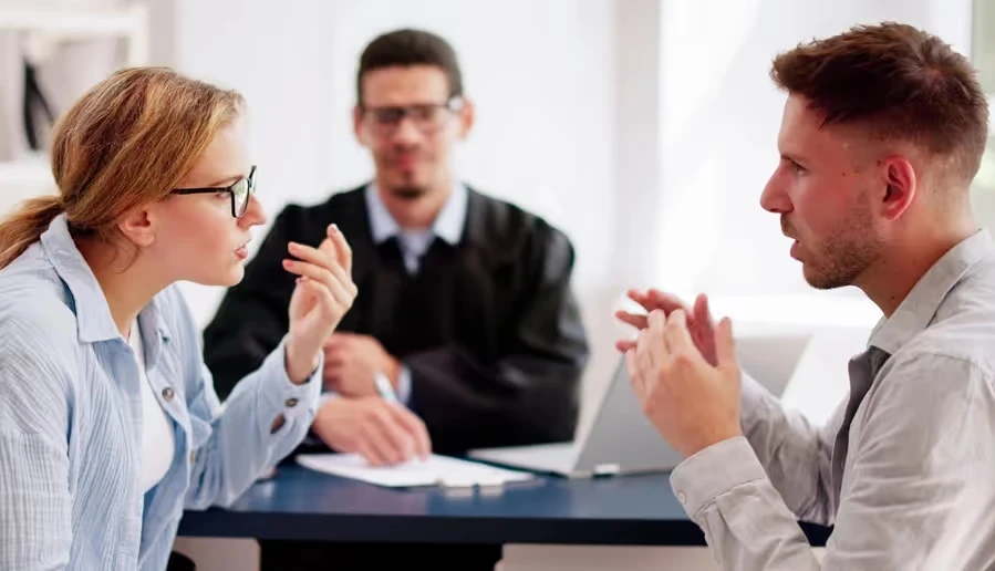 Couple arguing across a table in front of a judge