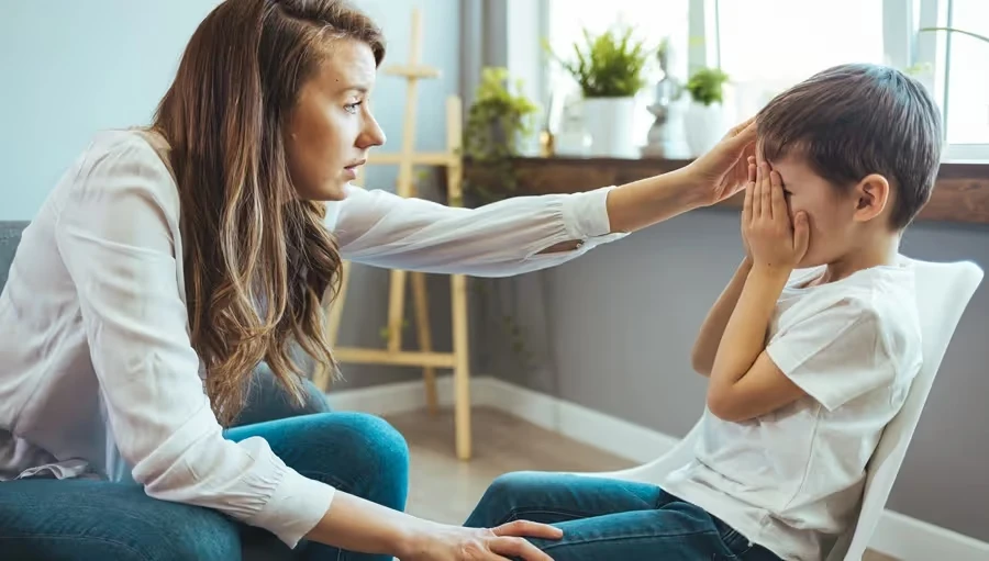 Mother reaching out to a boy covering his face with hands