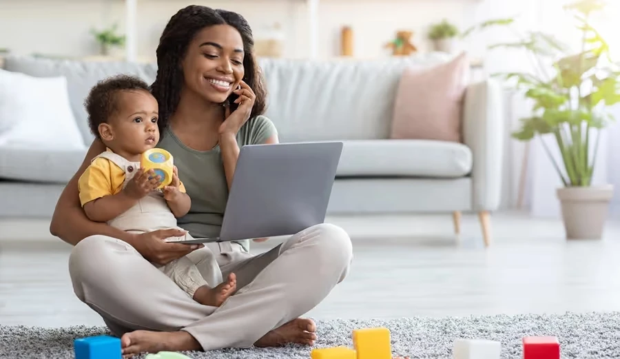 Mother on the phone with a laptop while holding her baby