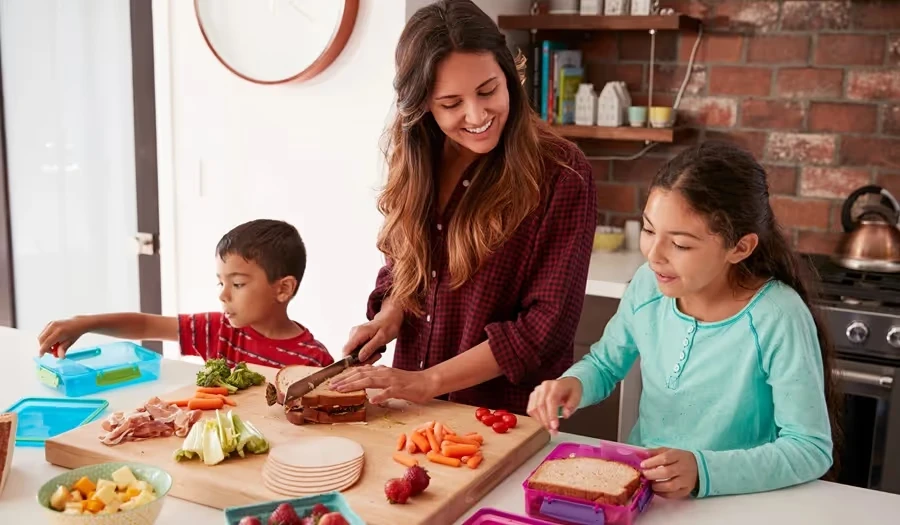 Mother making sandwiches with her two children in the kitchen
