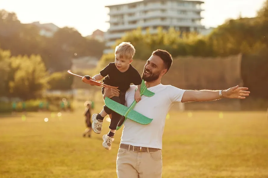 Father and son playing with a toy plane in a park