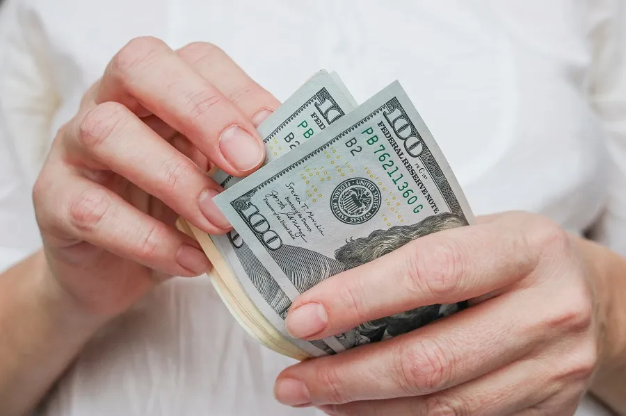 Hands counting out a fan of hundred-dollar bills