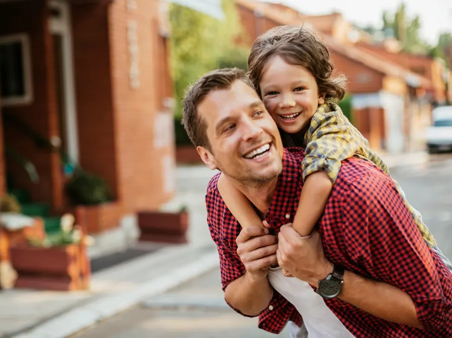 Smiling father carrying his laughing daughter on his back
