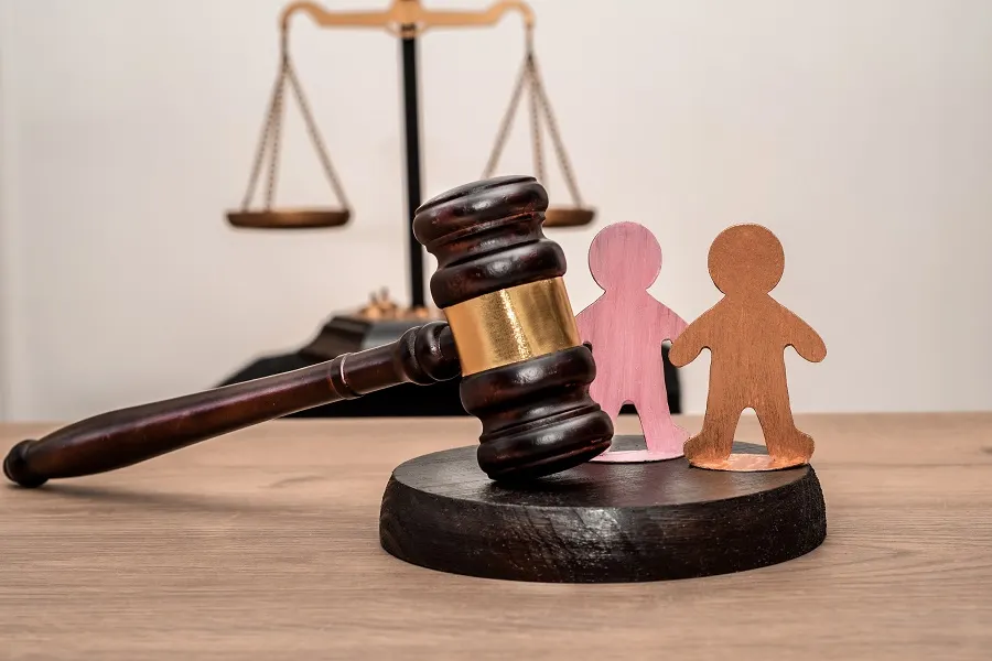 Scales of justice and a gavel with two paper child figures