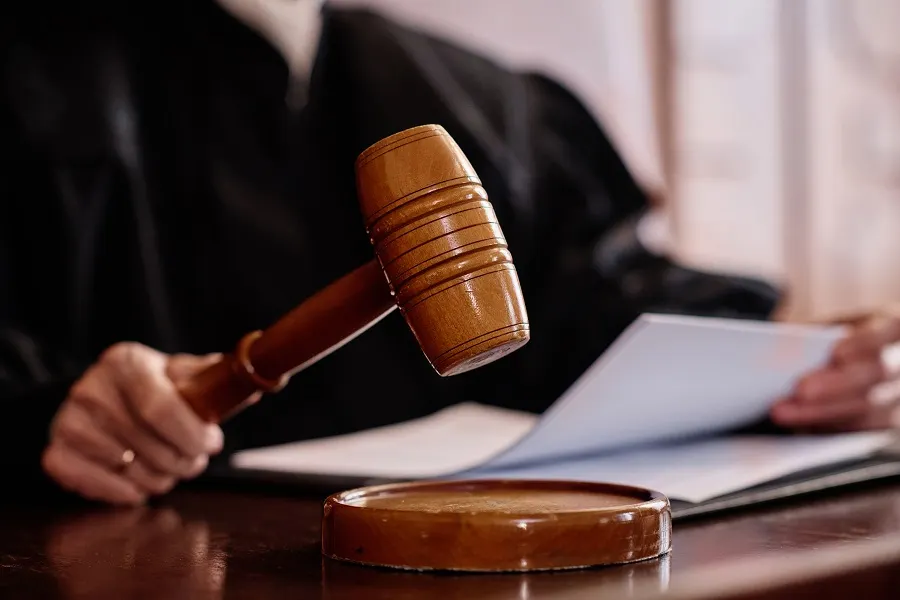 Judge raising a gavel over documents on the bench
