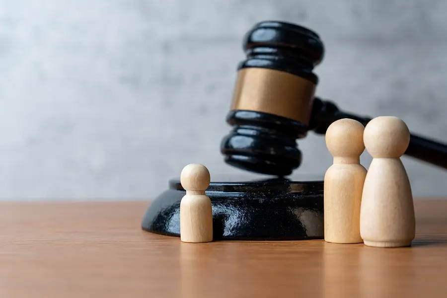 Gavel beside three wooden family figurines