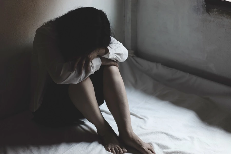 Woman sitting alone in the dark with her head on her knees