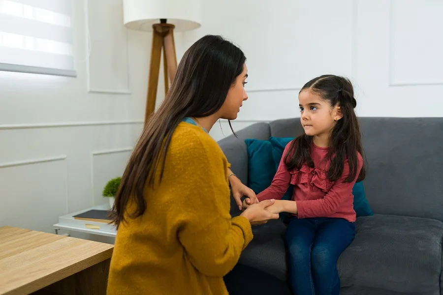 Mother sitting with her daughter and talking gently